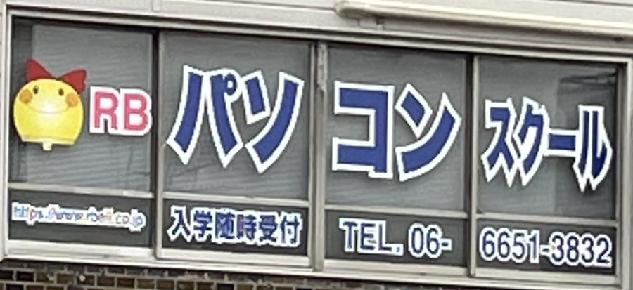 教室の看板。りぼんちゃんのキャラクターと「パソコンスクール」の文字が並ぶ、実際の店舗ウィンドウの写真